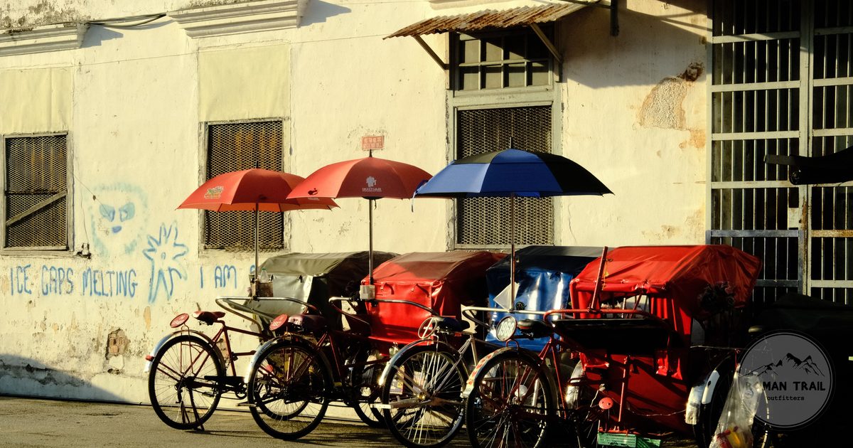 Trishaws with bright umbrellas parked on a George Town street in Penang