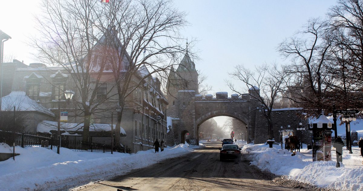 Snow-covered street and historic stone gate in Old Quebec, Canada