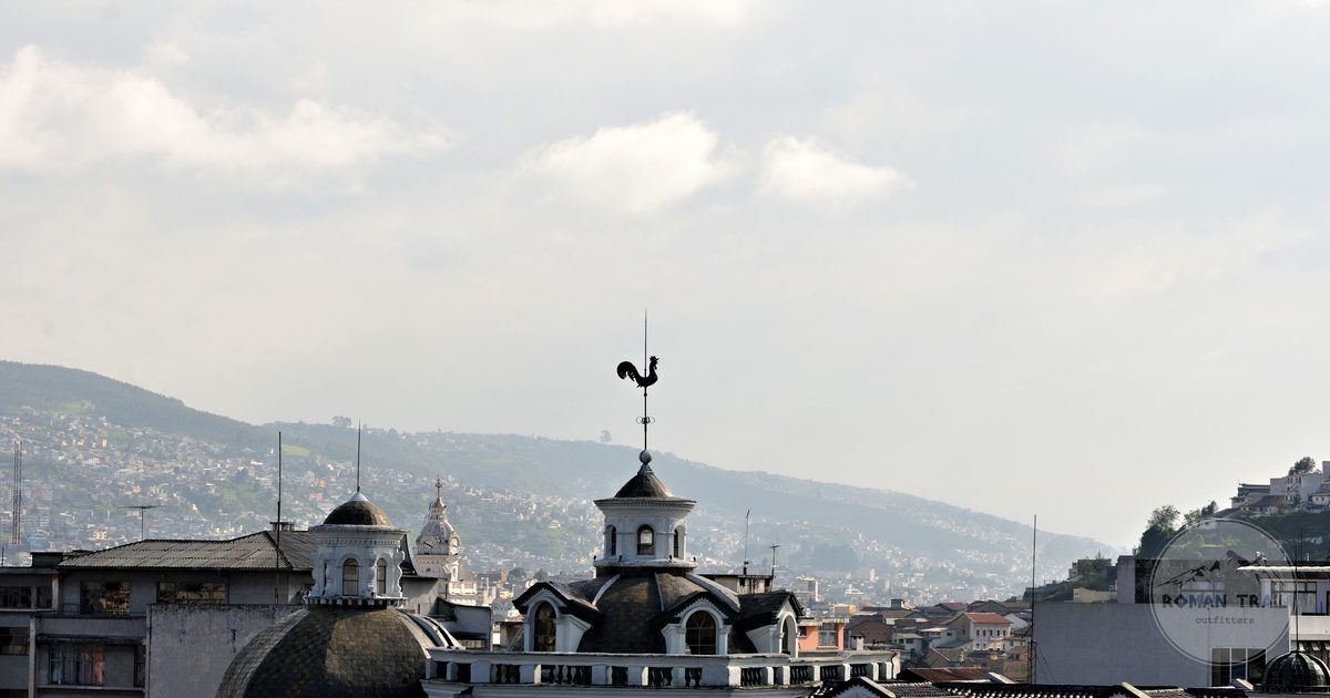 Tiled rooftops of colonial Quito with the Andes rising behind the city, Quito packing list for women by Roman Trail Outfitters