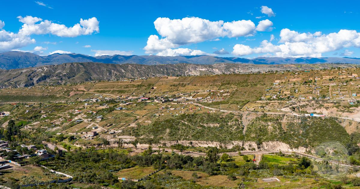 A Bolivian village set among green forested mountains under a clear sky