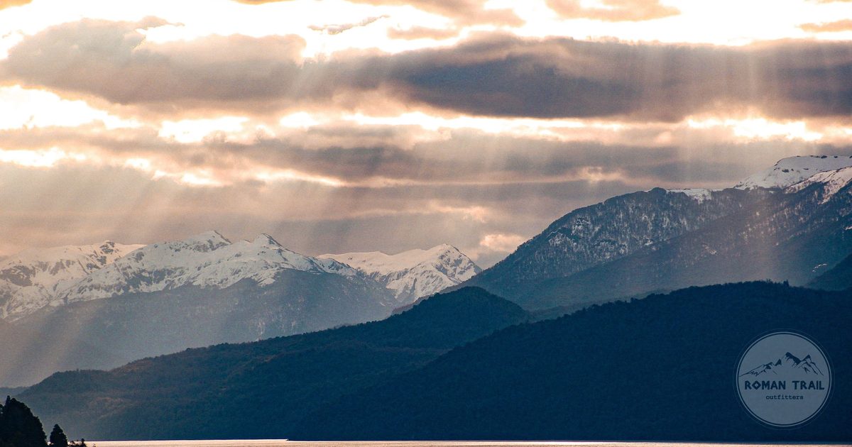 Sunbeams over a lake and snow capped mountains at San Martín de los Andes