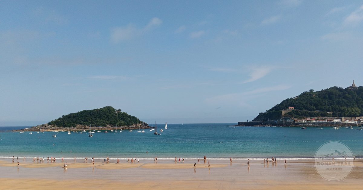 A beach with islands and sailboats under a bright sky, San Sebastian