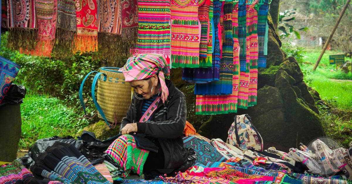 A vendor showing hand-embroidered ethnic minority textiles at a Vietnamese market
