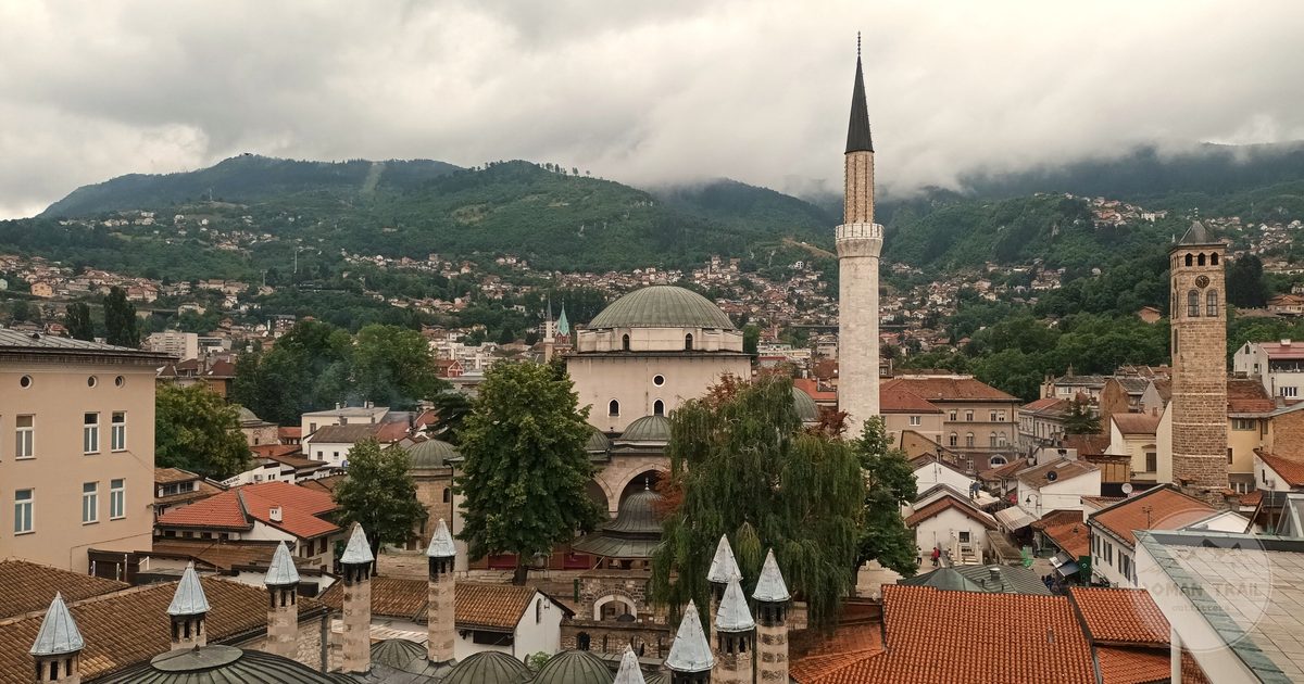 Aerial view of the rooftops and minarets of Sarajevo below green mountains