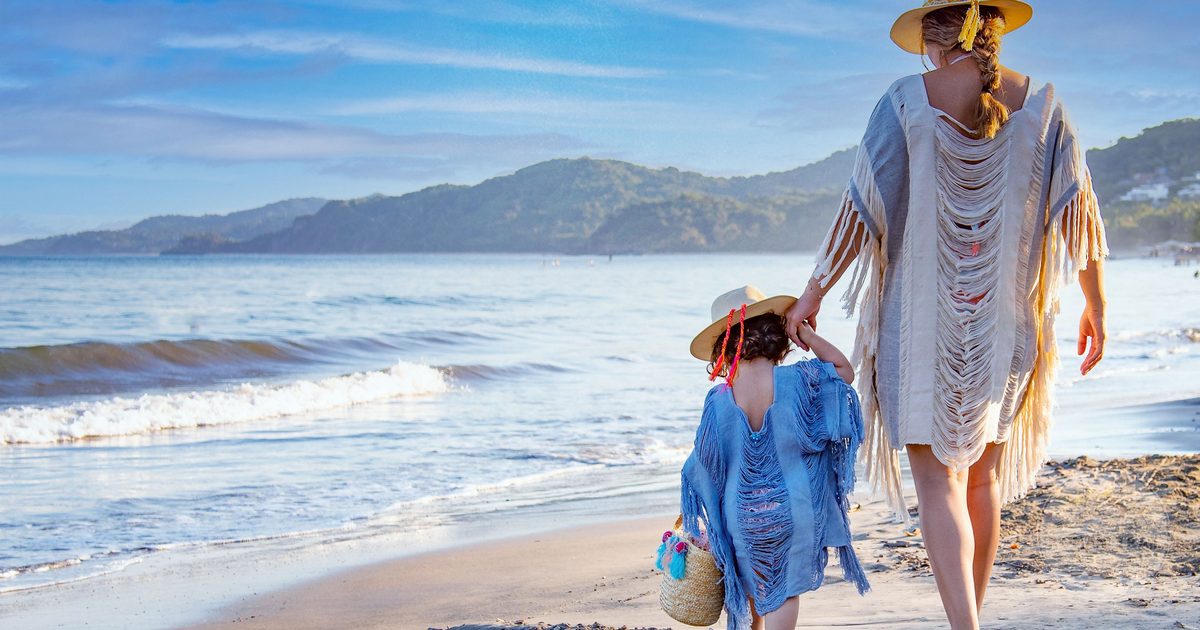 A mother and daughter walking along Sayulita beach on a sunny day, Mexico