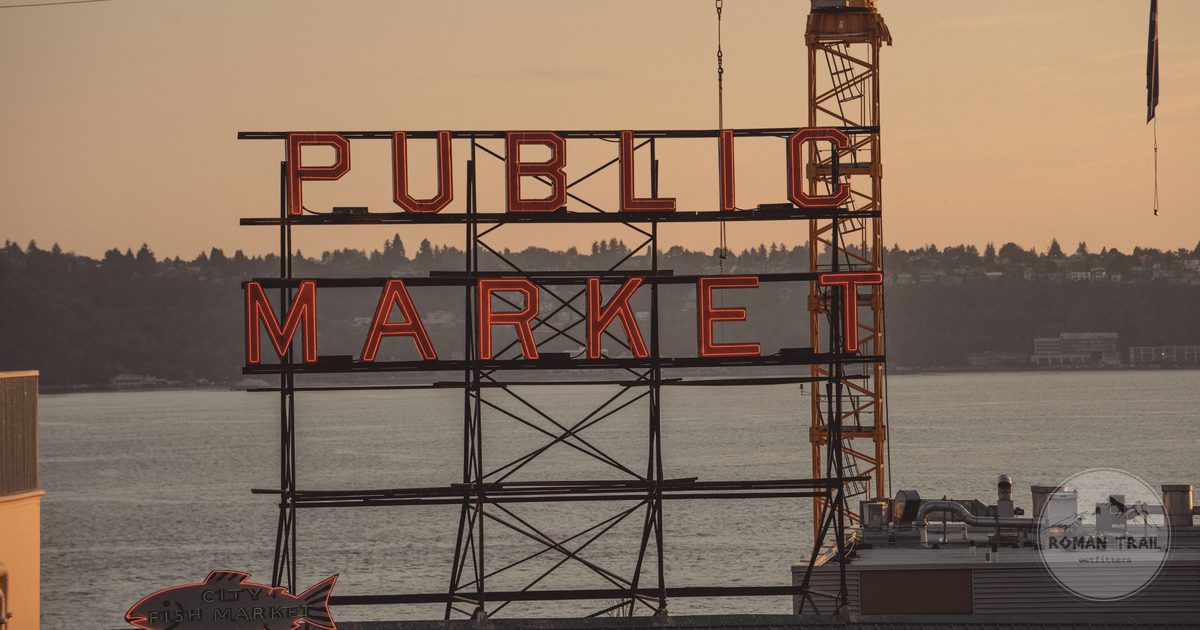 Pike Place Market Public Market neon sign at golden hour above Elliott Bay, Seattle for women travelers
