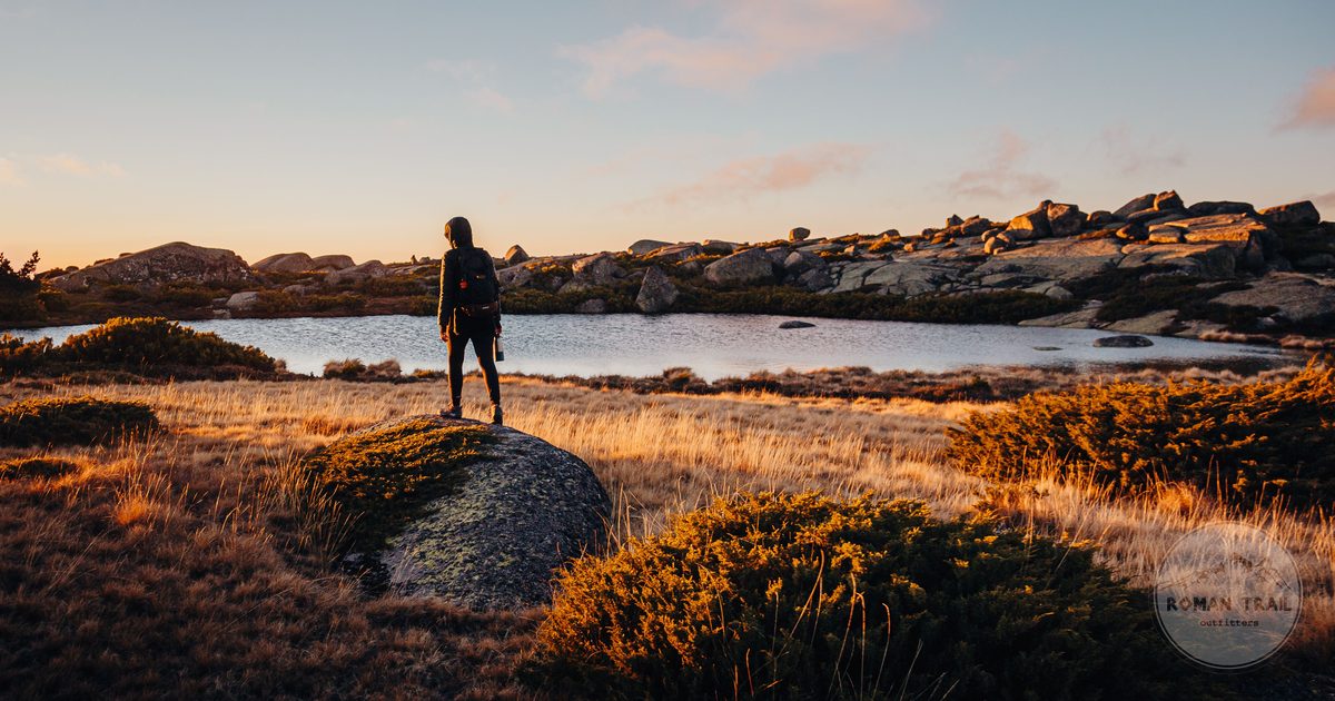 A hiker beside a lake at sunset in Serra da Estrela, Portugal
