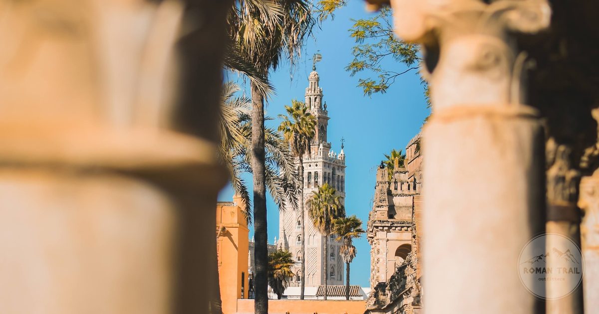 La Giralda seen between the columns of the Real Alcazar in warm afternoon light, Seville for women travelers