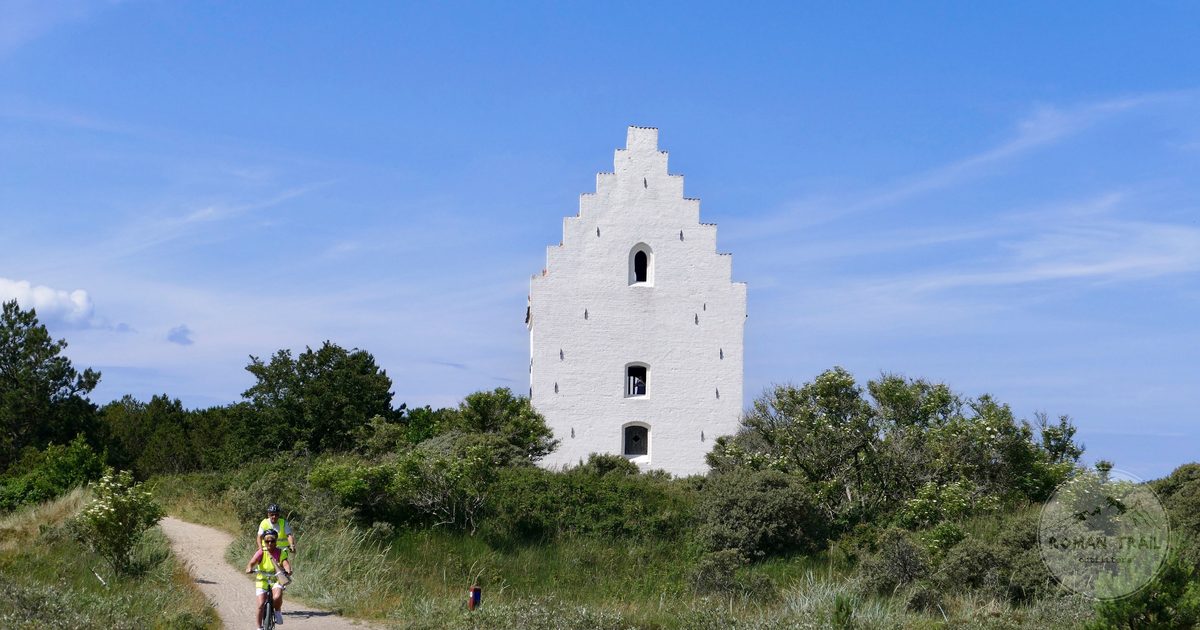 A cyclist passing the sand buried church at Skagen, Denmark
