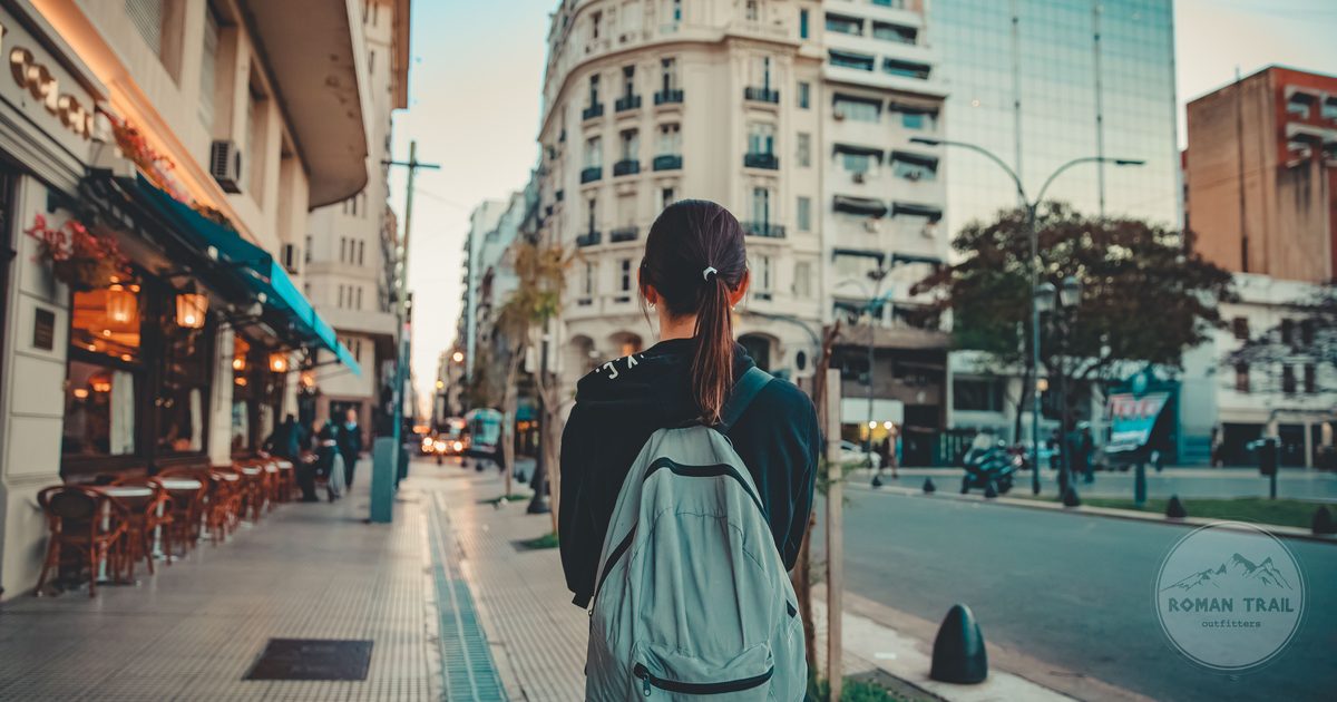 A woman walking a city street alone with a daypack on her back