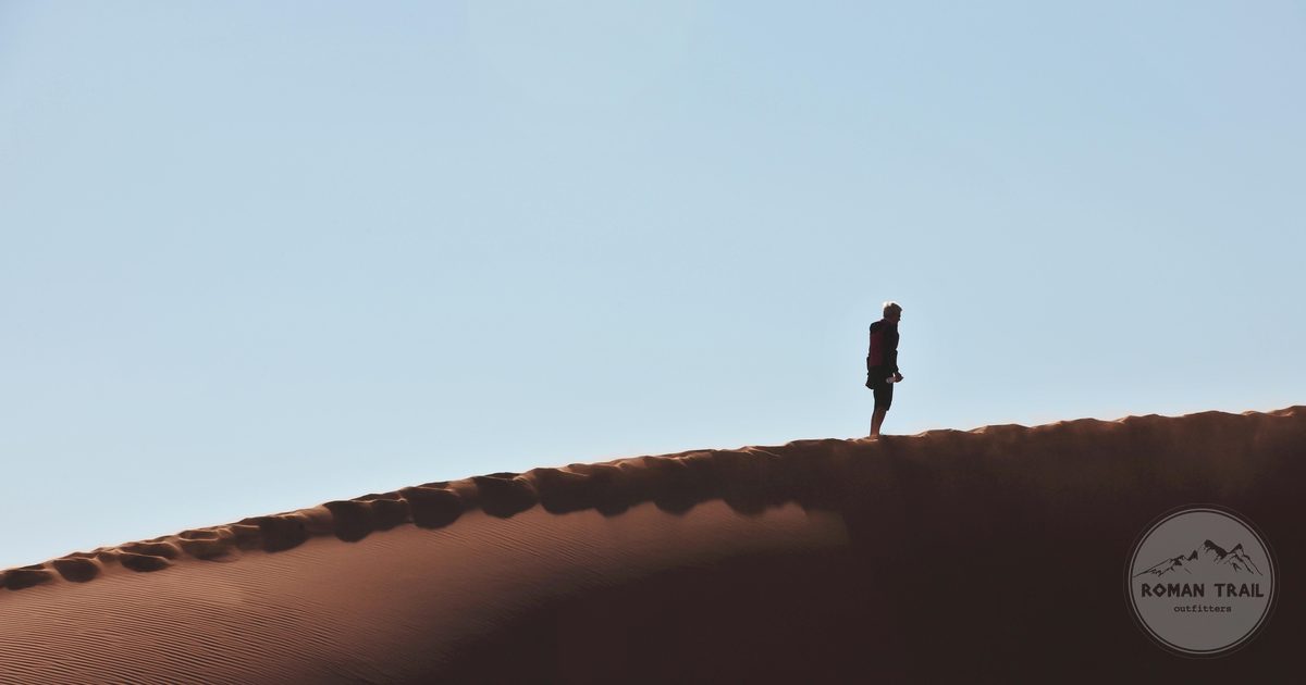 A lone hiker on a vast dune at Sossusvlei, Namibia