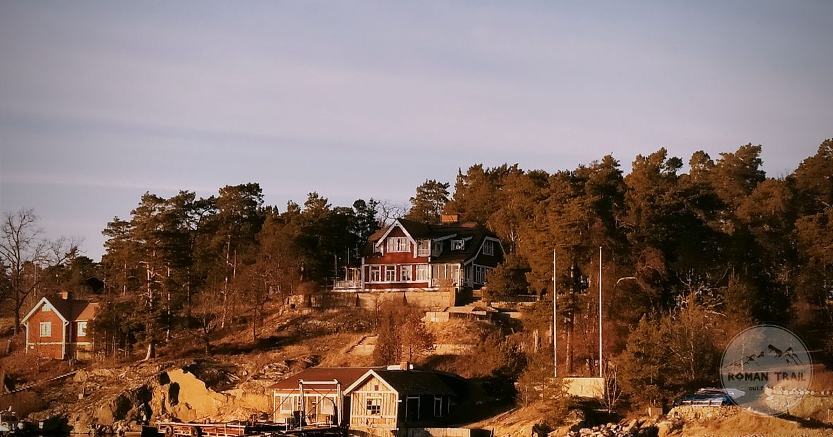 Red timber cottages on a wooded archipelago shore at sunset, Stockholm archipelago for women travelers
