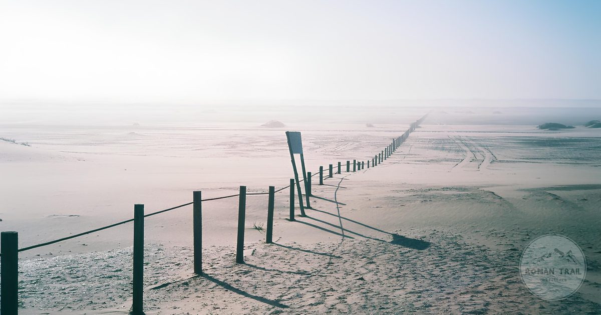 A fence fading into the coastal fog of the Namib Desert at Swakopmund, Namibia