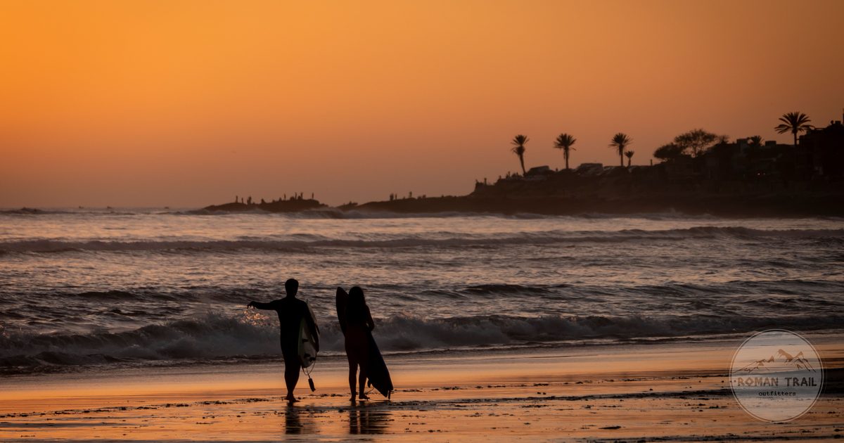 Surfers walking the beach at sunset in Taghazout, Morocco