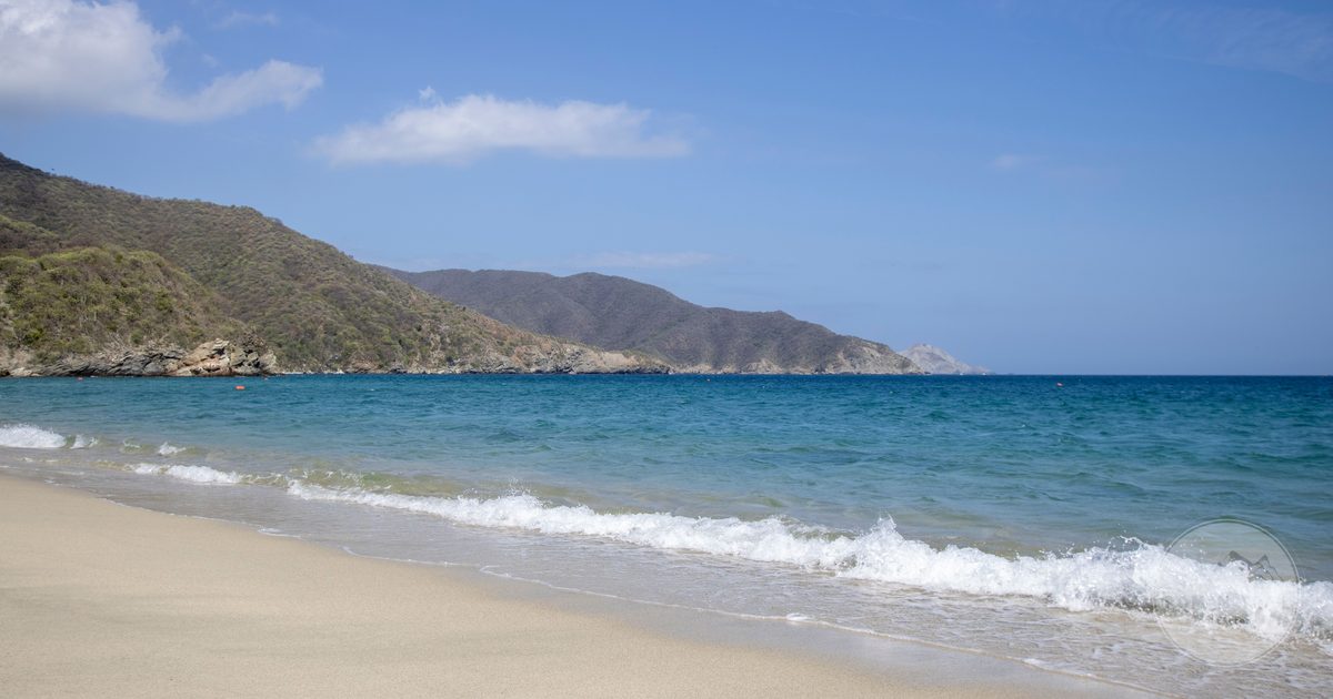 A sandy beach and green hills at Tayrona National Park, Colombia