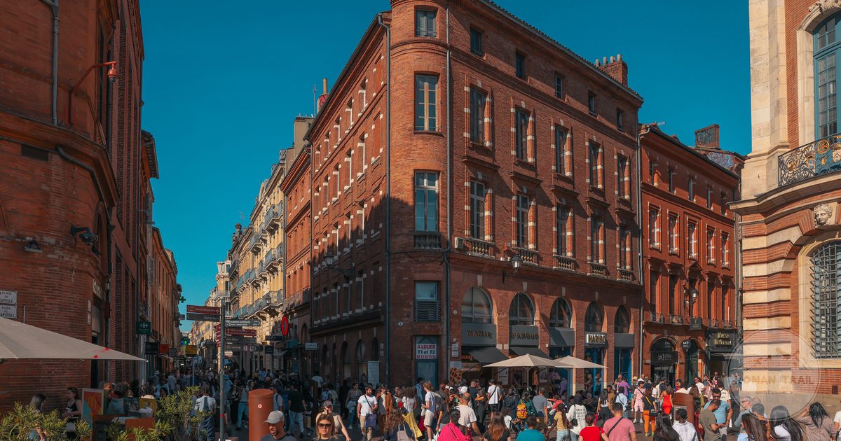 A busy street of red brick buildings in the historic centre of Toulouse