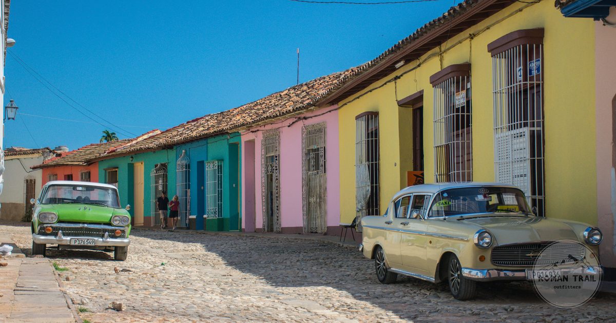 Vintage cars parked along colourful colonial houses in Trinidad, Cuba