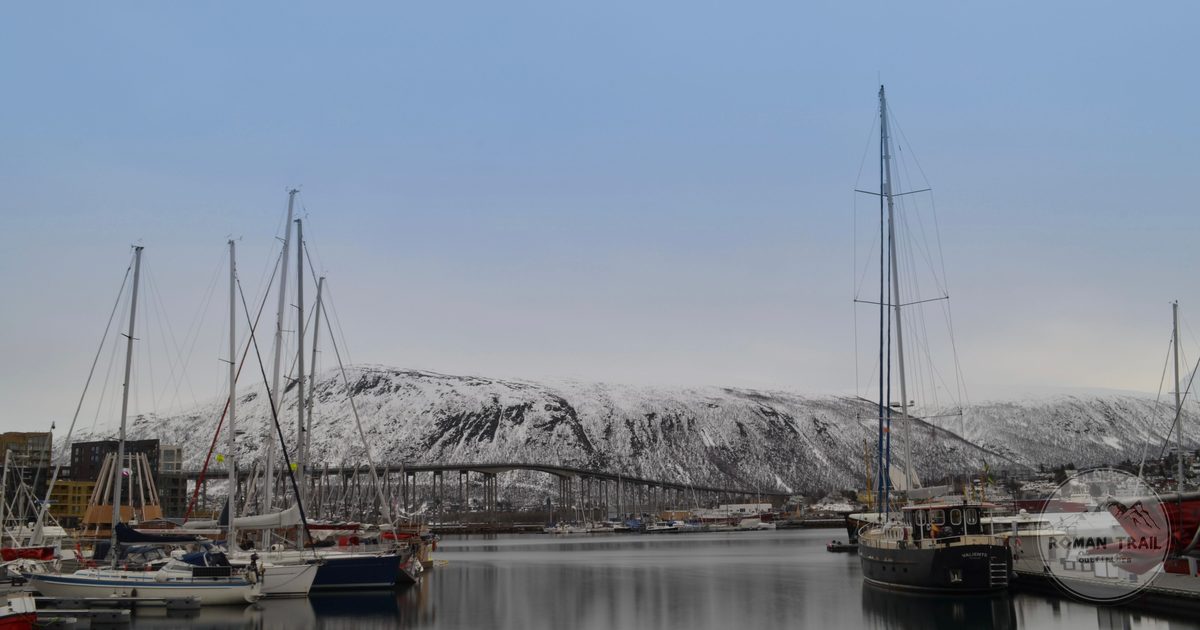 Tromso harbour with boats and snow-covered mountains in winter, Norway