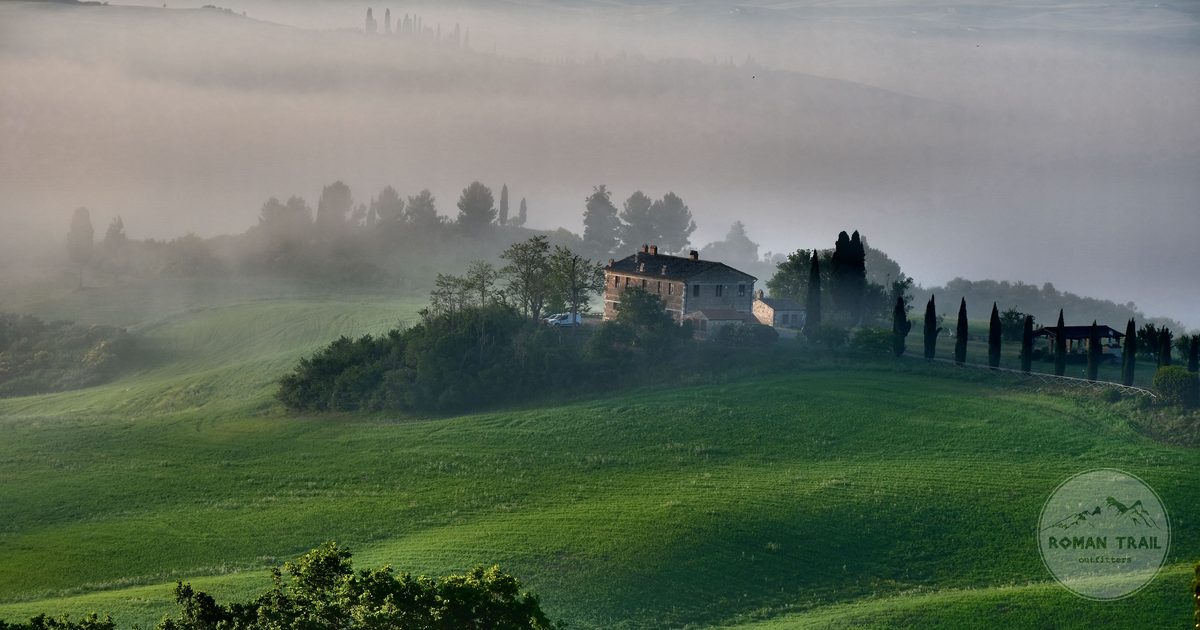 A misty Tuscan landscape with rolling hills and a farmhouse, Italy