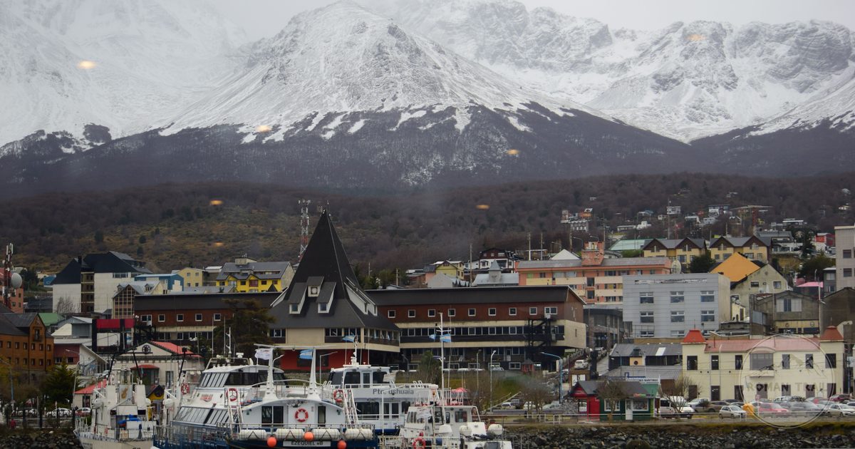 Boats in Ushuaia harbour below snow capped mountains at the end of Argentina, Ushuaia packing list for women by Roman Trail Outfitters