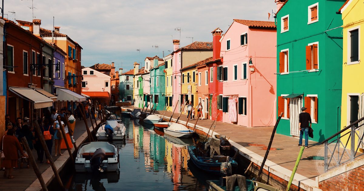 Colourful houses and moored boats along a canal in Burano, Venice