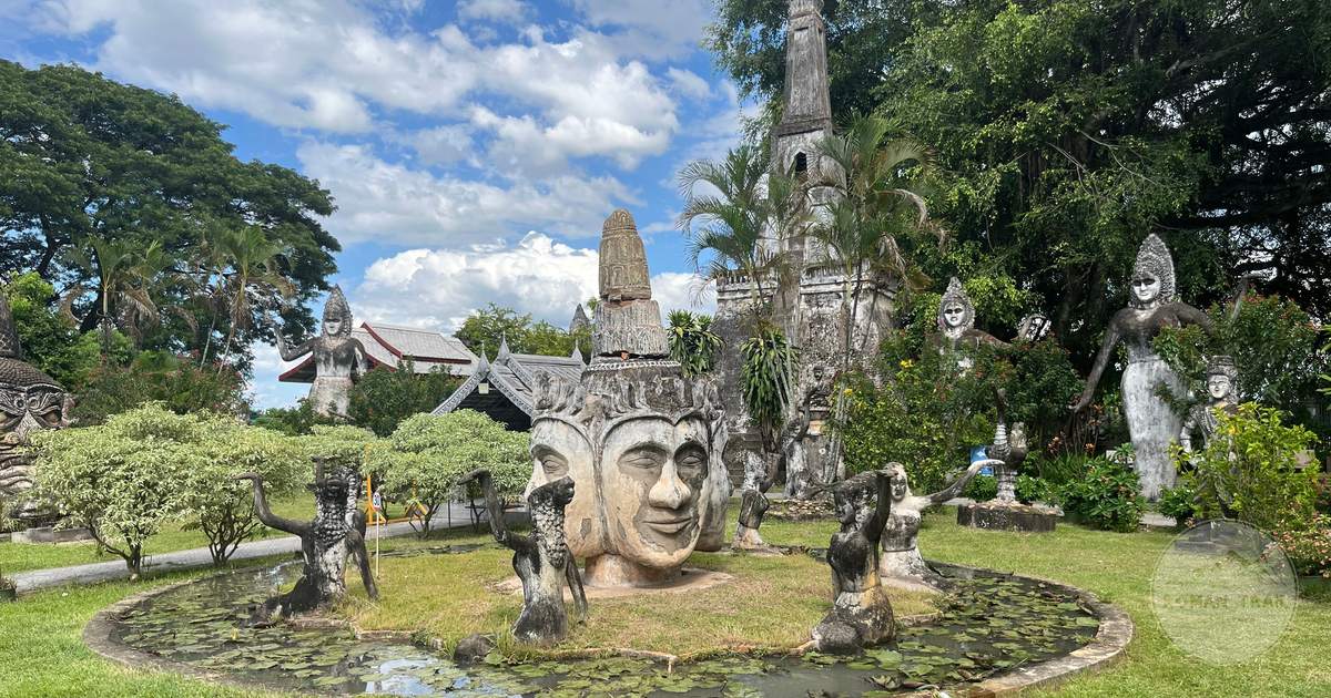 Buddha statues among greenery in a sculpture park in Laos under a bright sky