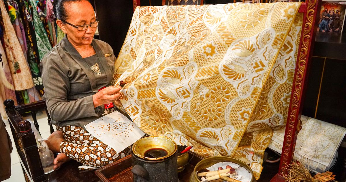 A craftswoman applying hot wax to fabric while making traditional batik in Yogyakarta, Yogyakarta packing list for women by Roman Trail Outfitters